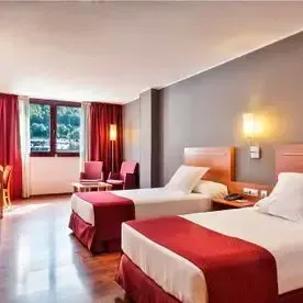 Una habitación de hotel con dos camas, una silla y una mesa.