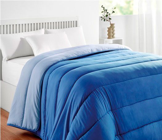 Una cama con un edredón azul y almohadas blancas