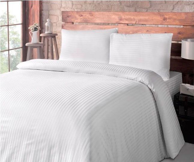 Una cama con un edredón blanco y almohadas en un dormitorio.