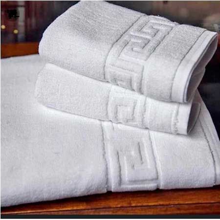 Tres toallas blancas están apiladas una encima de otra sobre una mesa de madera.