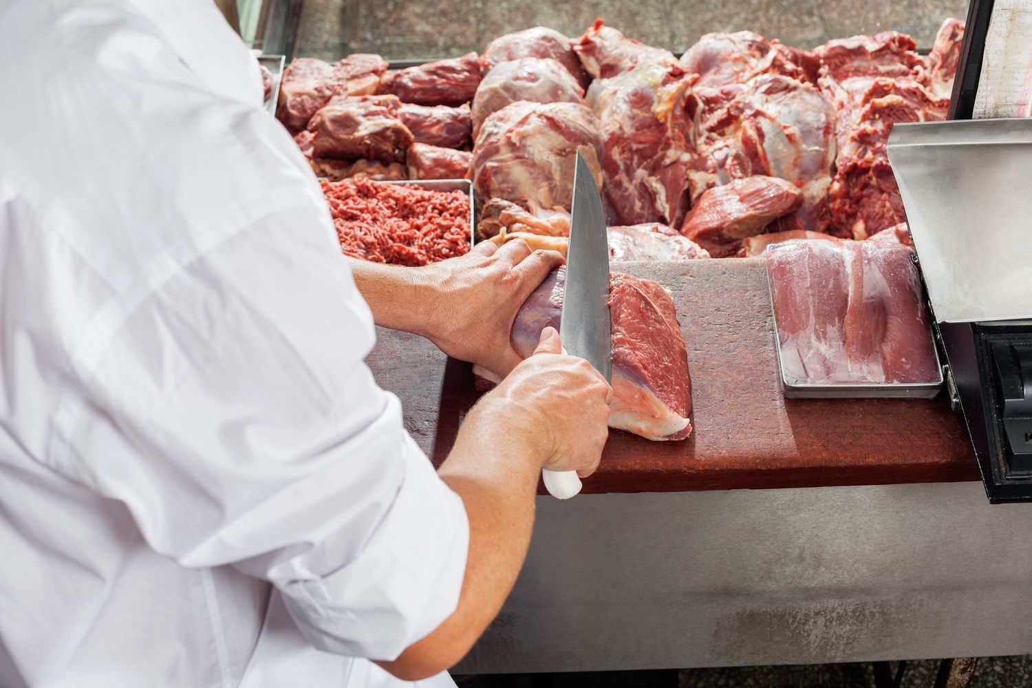 Una persona está cortando carne en una tabla de cortar.