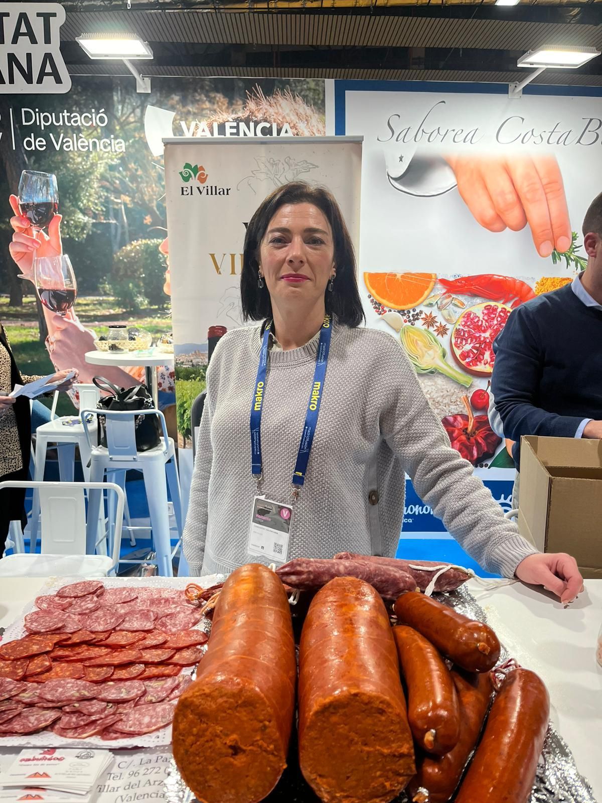 Una mujer está parada frente a una mesa llena de salchichas.