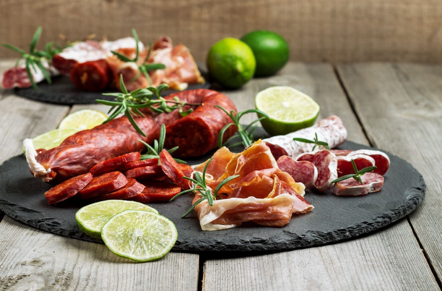 Una variedad de carnes y verduras en una tabla de cortar sobre una mesa de madera.