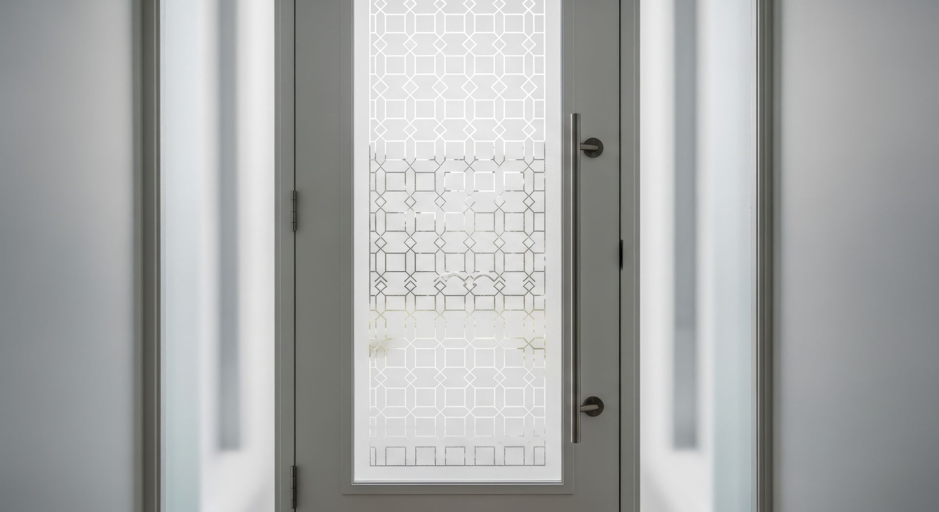 Porte d'entrée moderne en verre dépoli à motifs géométriques dans un couloir lumineux