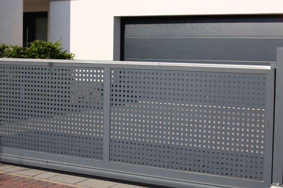 Portail d'allée en métal perforé gris devant une maison et un garage modernes