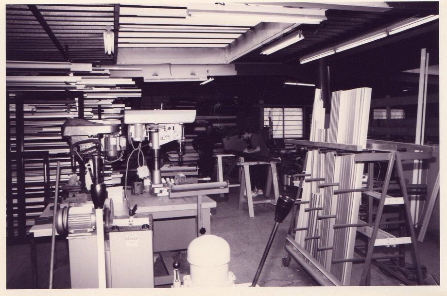 Atelier encombré d'étagères, d'outils et de planches de bois dans une pièce sombre