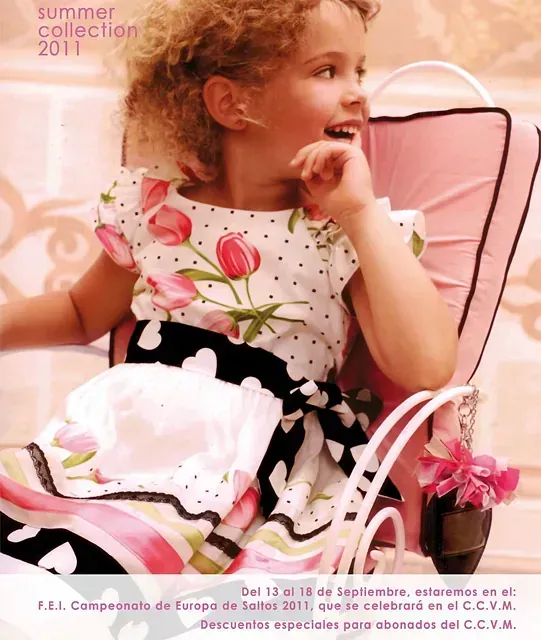 Chica joven con vestido floral sentada en un carruaje rosa, con aspecto feliz. Colección de verano 2011.