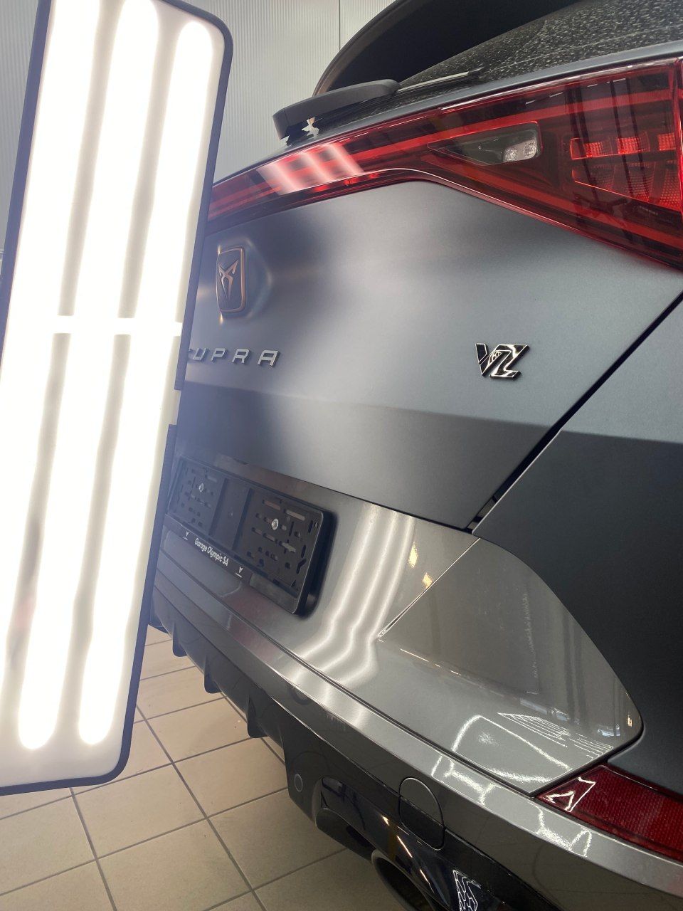 Une voiture grise est garée dans un garage à côté d'une lumière.