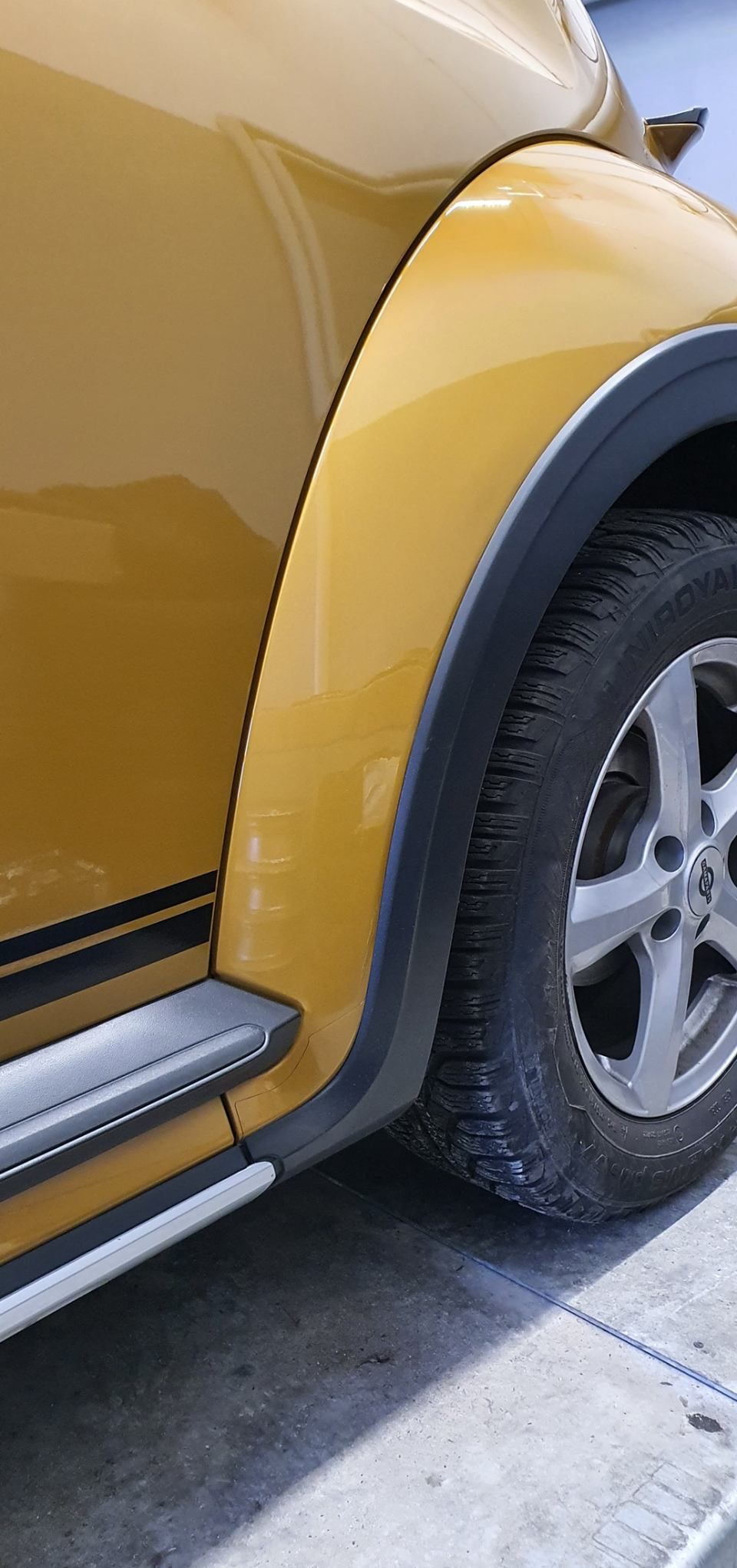 Une voiture jaune est garée sur le bord de la route.