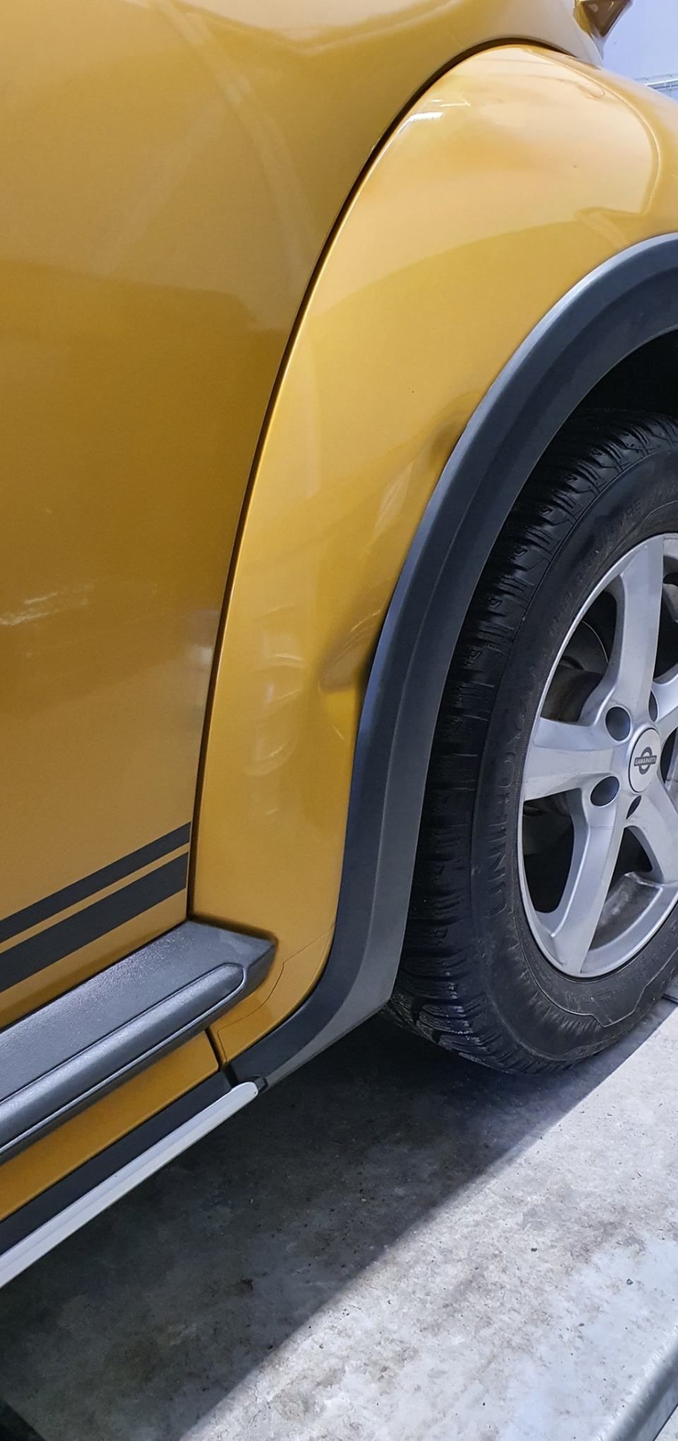 Une voiture jaune est garée sur le bord de la route.