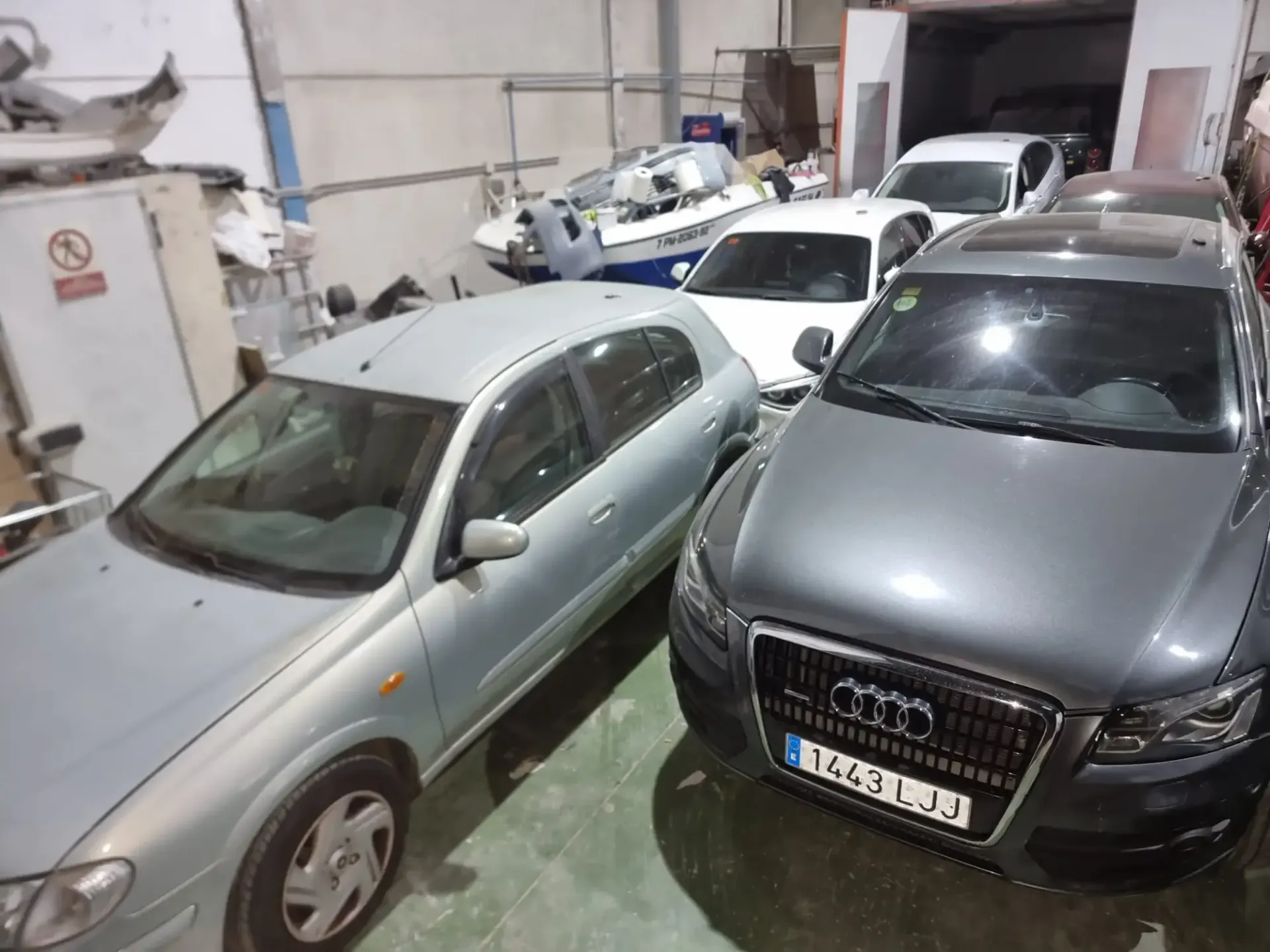 Aparcamiento cubierto con varios coches estacionados, entre ellos un Audi gris en primer plano.