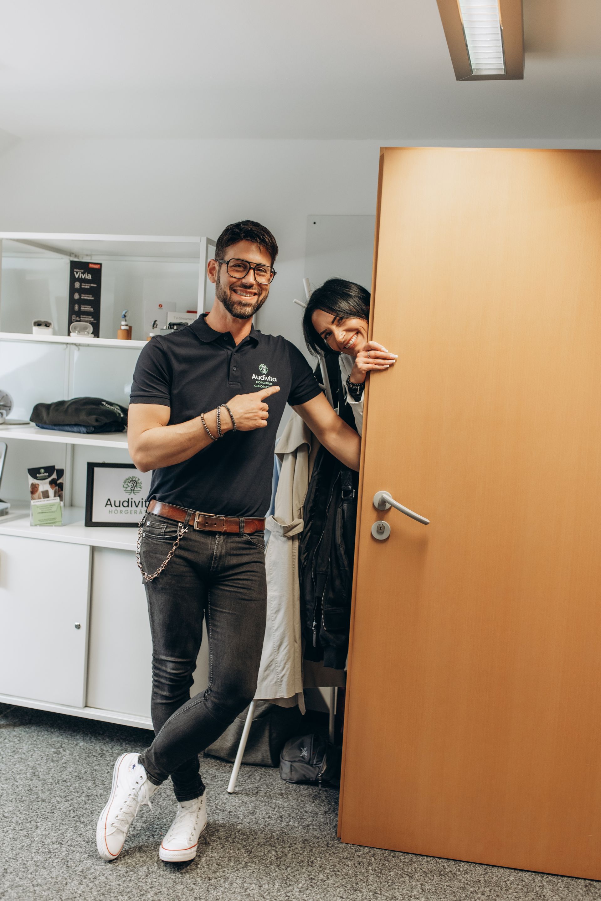 Frau in einem dunklen Blazer sitzt lächelnd auf einem orangefarbenen Stuhl.
