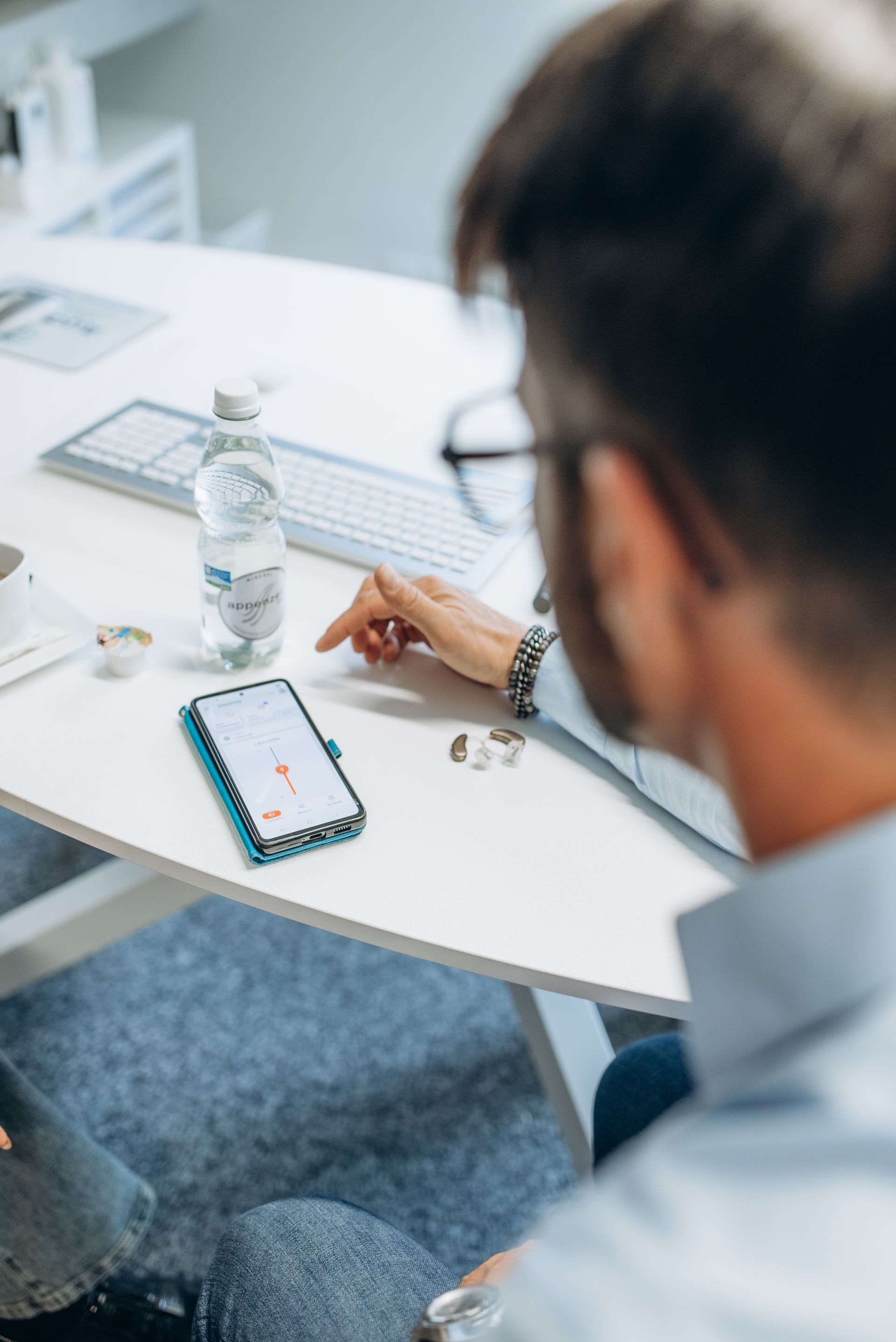 Mann und Frau posieren neben einem Auto, der Mann trägt eine Brille und einen Rollkragenpullover, die Frau ein schwarzes Top und Jeans, beide lächeln.