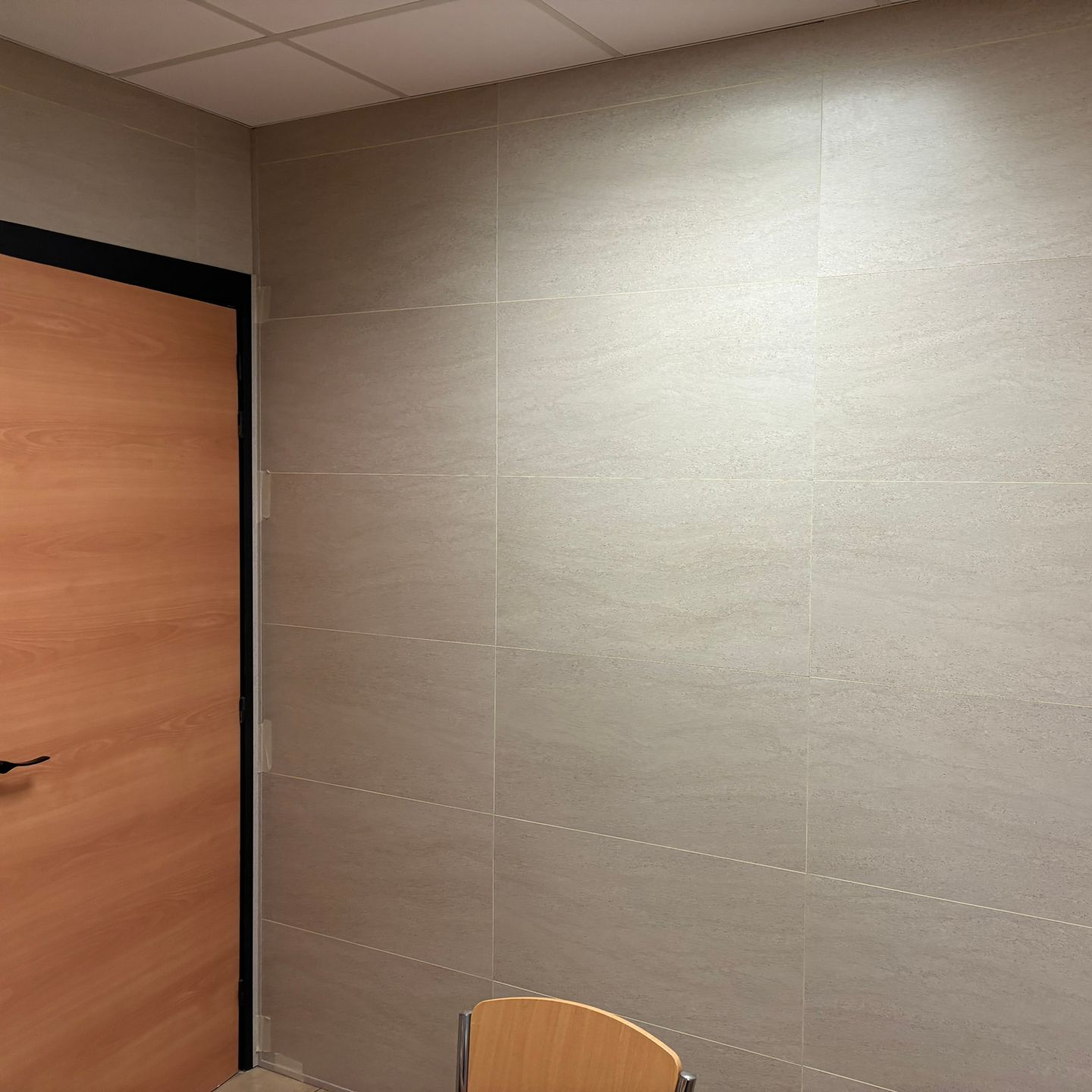 Une fresque murale pour chambre d'enfant représentant de douces collines roses, des arbres verts, un hibou et des koalas en peluche assis sur des souches et des étagères en bois.