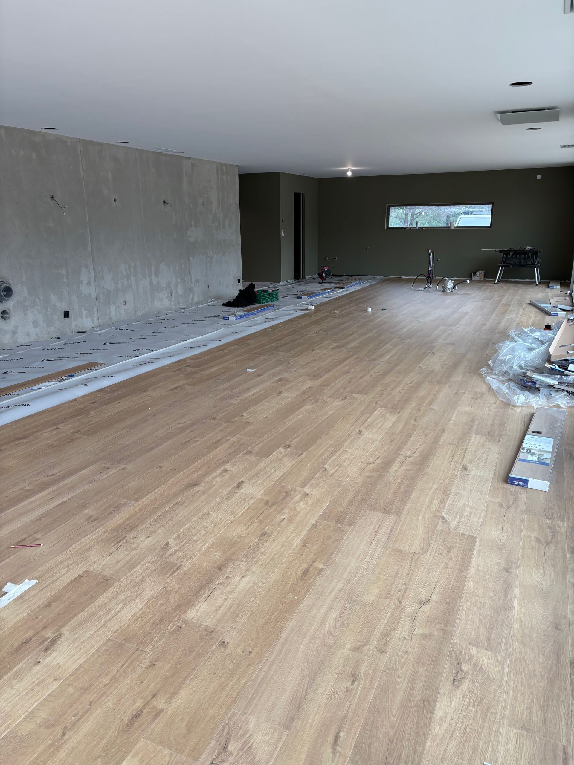 Cuisine et salle à manger modernes et minimalistes avec parquet clair, un îlot avec tabourets de bar et de hautes étagères métalliques.