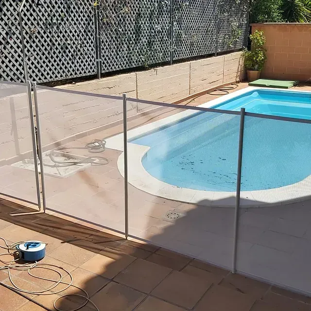 Una valla rodea una piscina con agua azul.