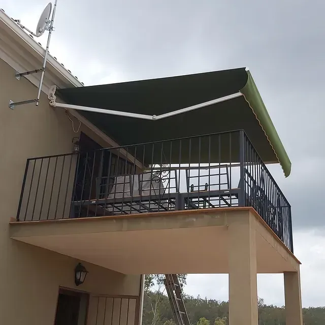 Un balcón con un toldo verde encima.
