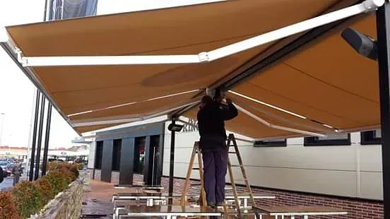 Un hombre está de pie en una escalera debajo de un toldo.