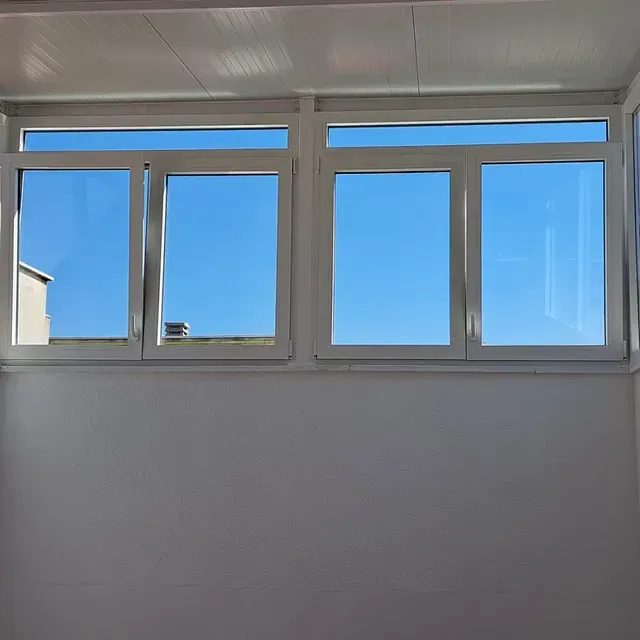 Una habitación con muchas ventanas y un cielo azul detrás de ellas.