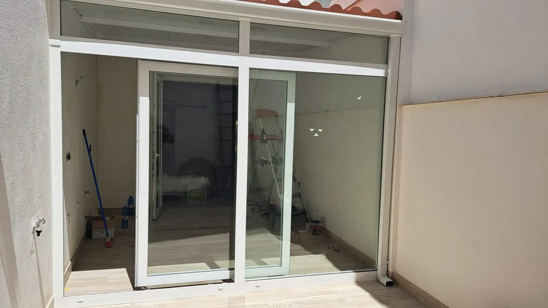 Hay una puerta corrediza de vidrio en el patio trasero de una casa.