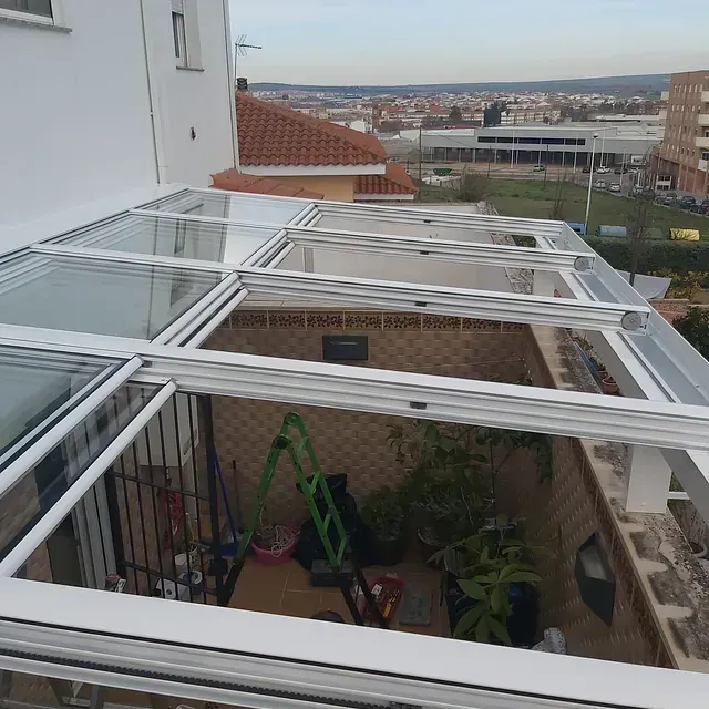 Un edificio blanco con techo de cristal y una escalera verde.