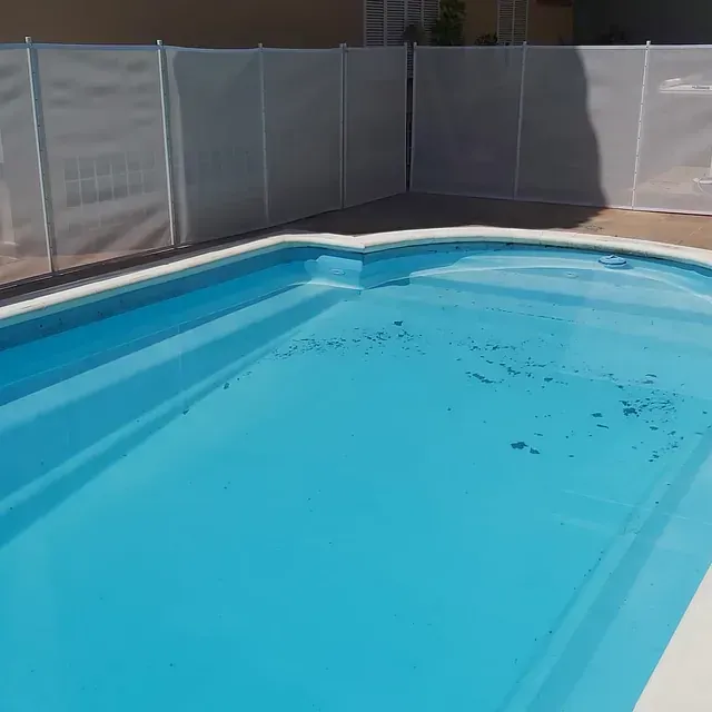 Una gran piscina rodeada por una valla blanca.