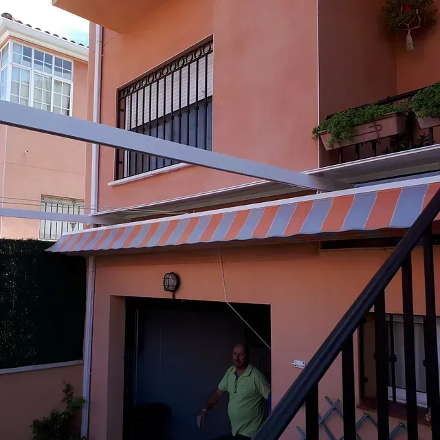 Un hombre con una camisa verde está de pie debajo de un toldo de rayas.