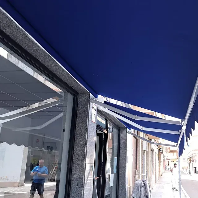 Un hombre con una camisa azul está parado debajo de un toldo azul.