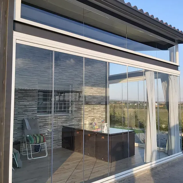 Un patio con jacuzzi y sillas detrás de una pared de vidrio.