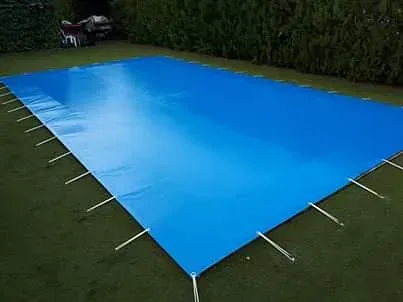 Una gran lona azul se encuentra encima de una piscina.