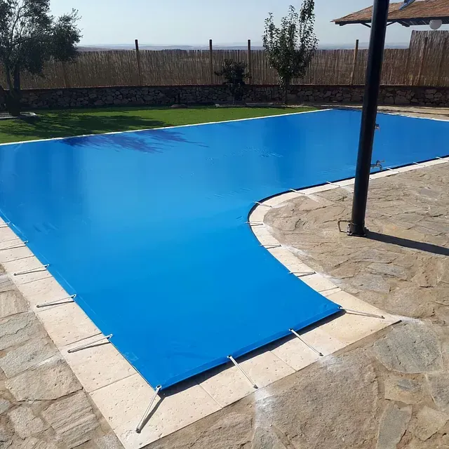 Una lona azul cubre una gran piscina.