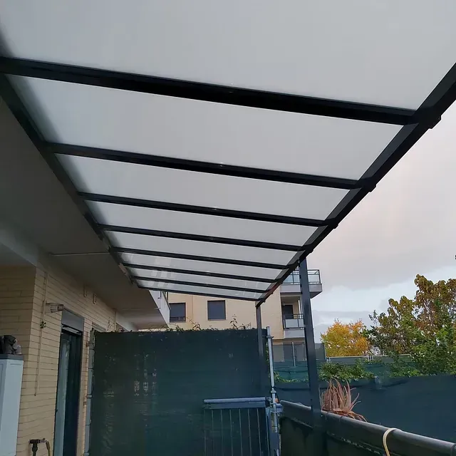 Un balcón con un dosel encima y un edificio al fondo.