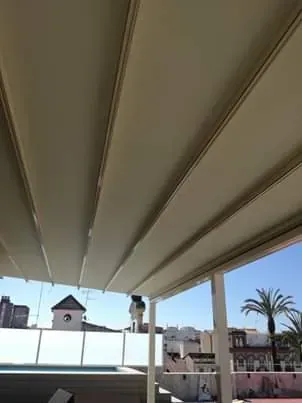 Una pérgola blanca se encuentra encima de un balcón con vistas a una piscina.