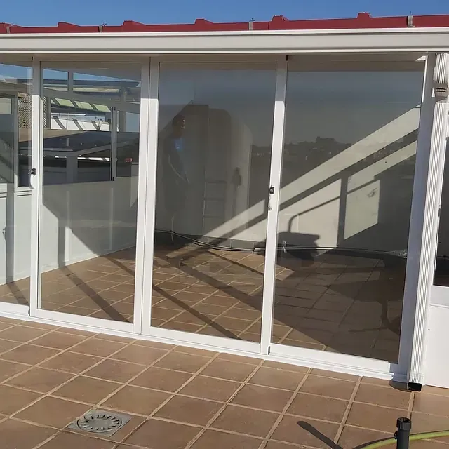 Un edificio blanco con puertas corredizas de vidrio y un techo rojo.