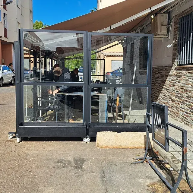Un grupo de personas están sentadas en mesas bajo un toldo afuera de un restaurante.