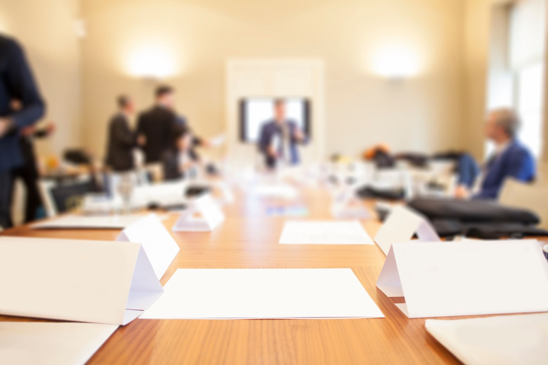 Salle de réunion avec plusieurs personnes en arrière-plan et des documents en papier sur la table