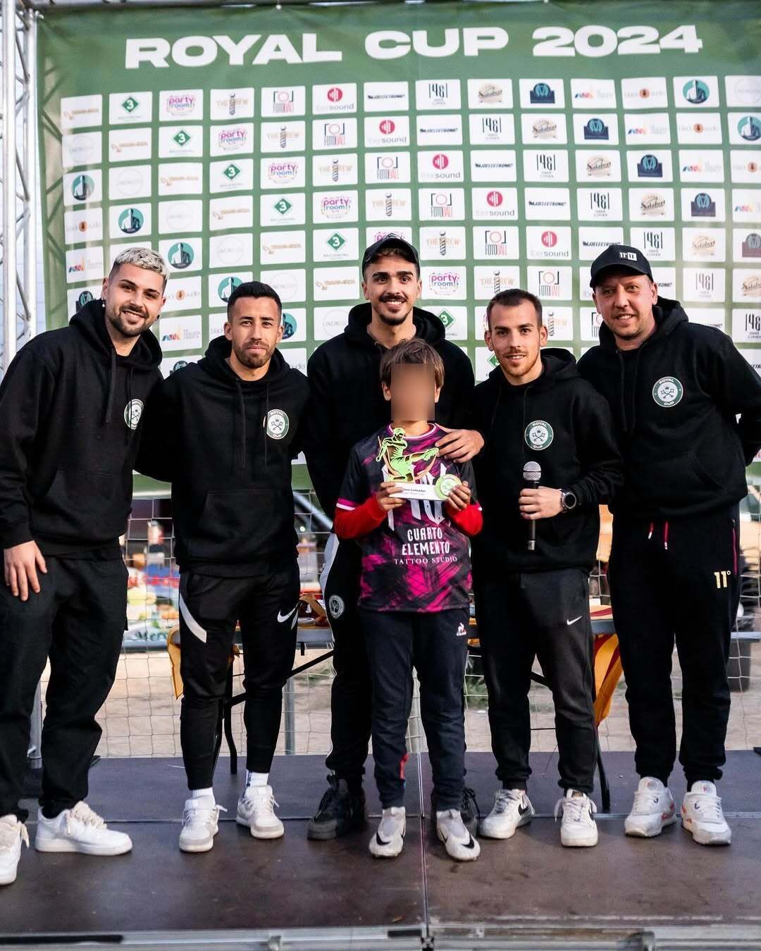 Grupo de seis personas, incluido un niño, en un escenario con un telón de fondo de la