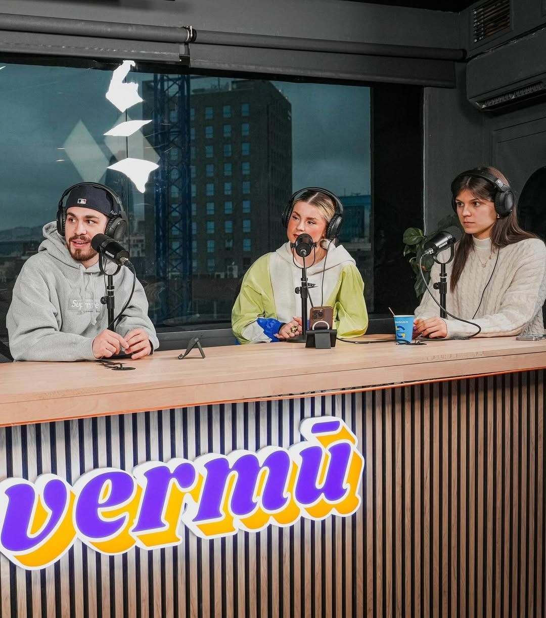 Grabación de podcast con tres personas en un escritorio. Logotipo amarillo de