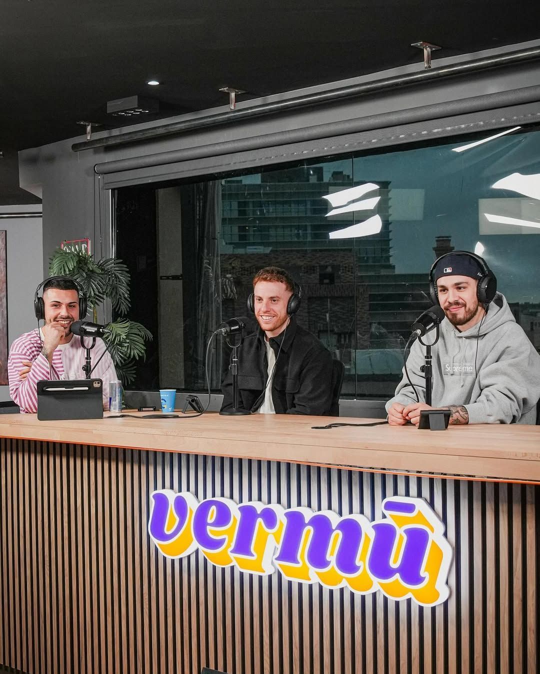 Tres personas sentadas a la mesa de un podcast con el logo de