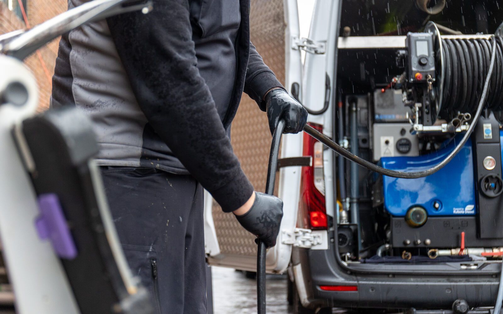 Ein Mann hält einen Schlauch vor einem Lieferwagen.