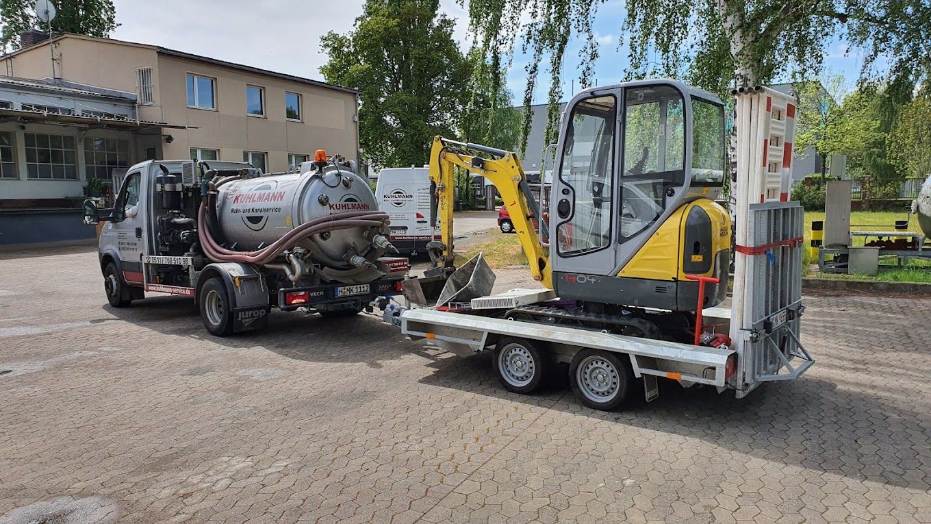 Ein LKW zieht einen kleinen Bagger auf einem Anhänger.