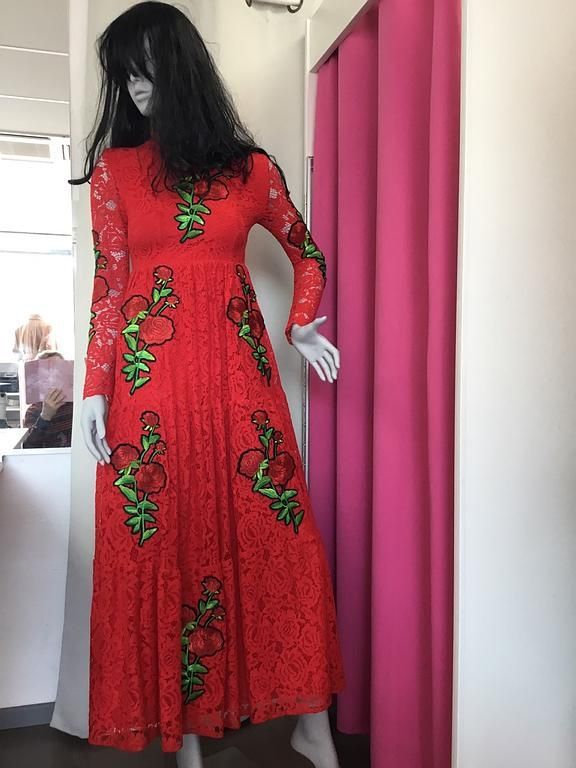 Robe longue rouge ornée de motifs floraux verts.