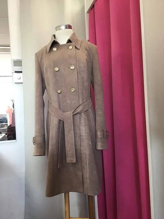 Manteau long en daim beige avec ceinture et boutons dorés.