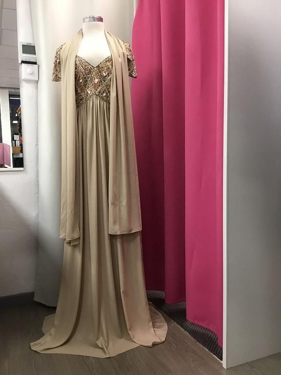 Robe fluide beige ornée de perles, accompagnée d'un foulard assorti, idéale pour une tenue raffinée.