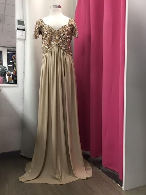 Robe longue fluide de couleur beige, ornée de perles subtiles, parfaite pour une occasion raffinée.
