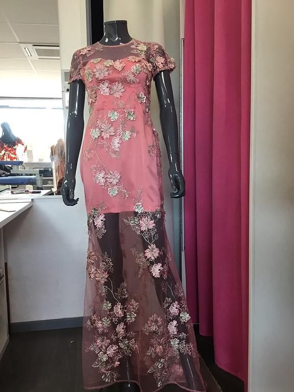 Robe longue rose avec une jupe en tulle transparent ornée de broderies florales délicates.
