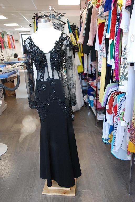 Robe noire élégante avec détails brodés scintillants, dotée de manches longues, parfaite pour une soirée chic.