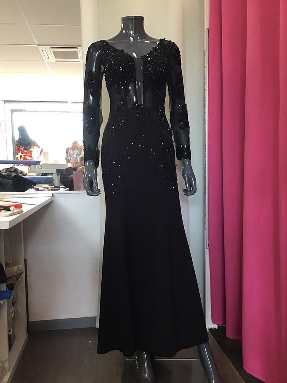 Robe de soirée noire longue avec des manches transparentes ornées de broderies, idéale pour un événement formel.