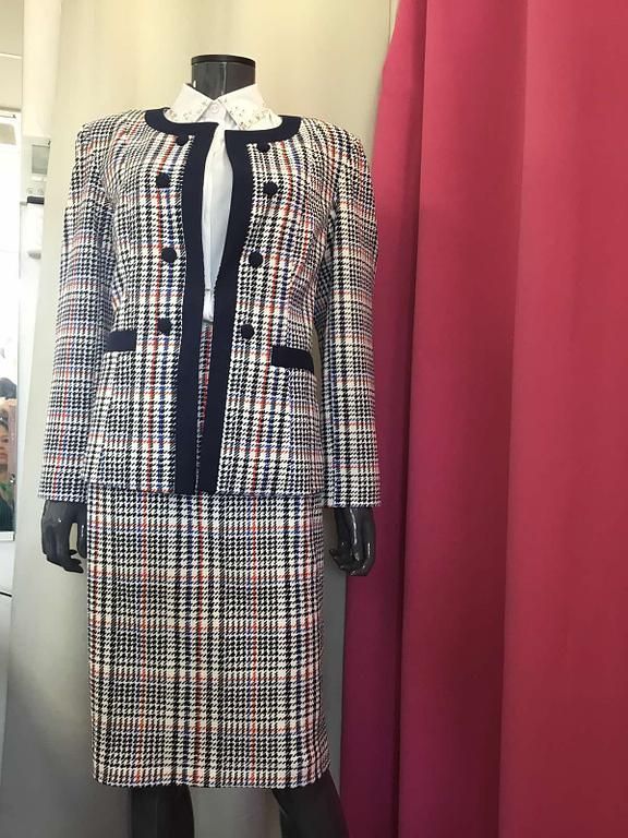 Tailleur gris texturé avec des bordures noires contrastantes, composé d'une veste et d'une jupe, pour un look chic.