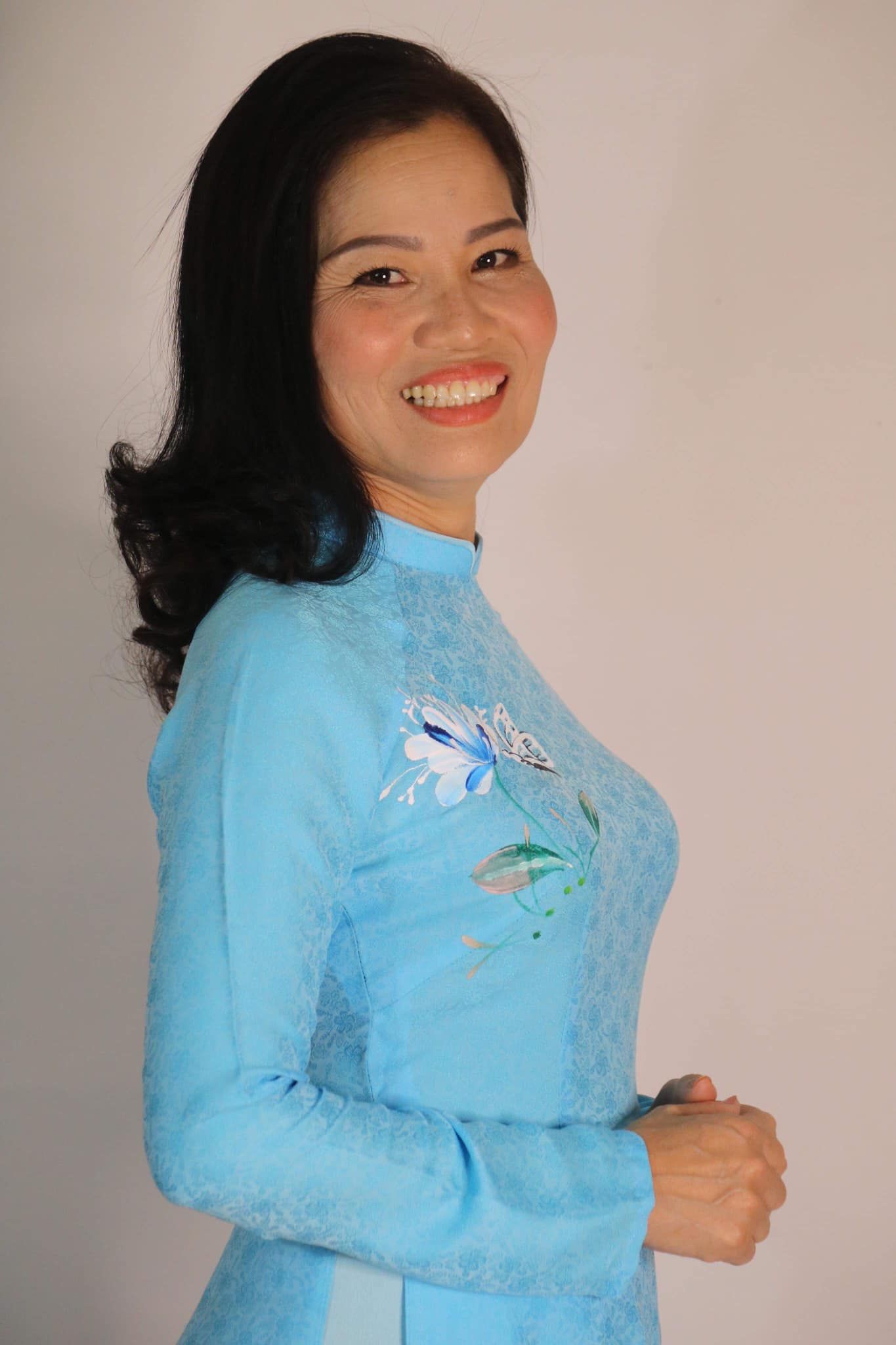 Couturière en Ao Dai bleu avec broderies florales.